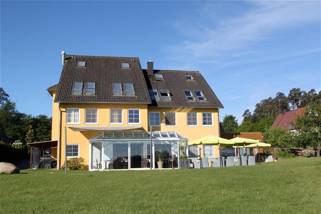 una grande casa gialla con un prato davanti di Hotel am Müritz-Nationalpark a Waren