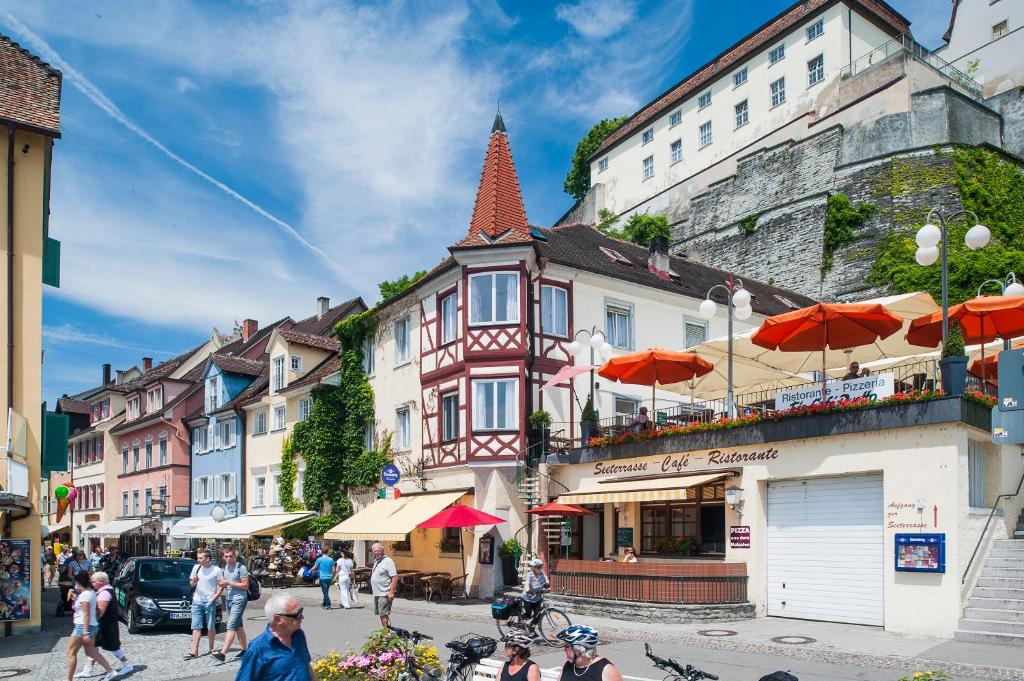 um grupo de pessoas andando por uma rua com edifícios em Ferienwohnungen zum Nachtwächter em Meersburg