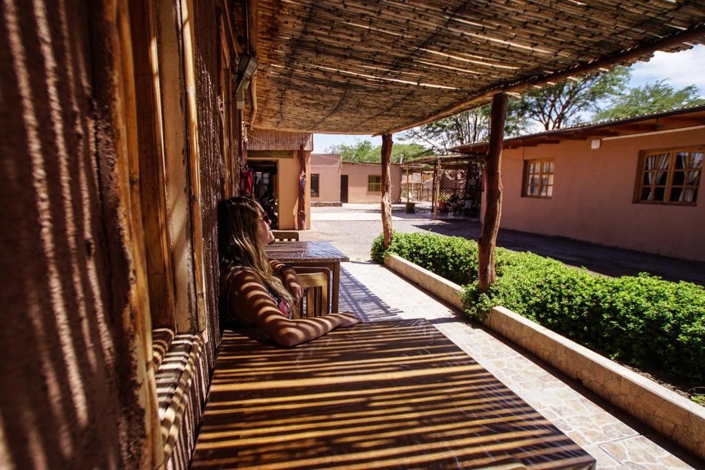 una mujer sentada en el porche de un edificio en Casa Lickana B&B, en San Pedro de Atacama