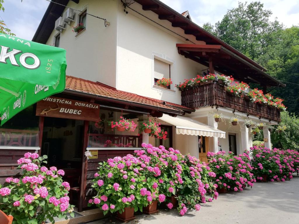 un edificio con muchas flores delante de él en Domačija Bubec, en Ilirska Bistrica
