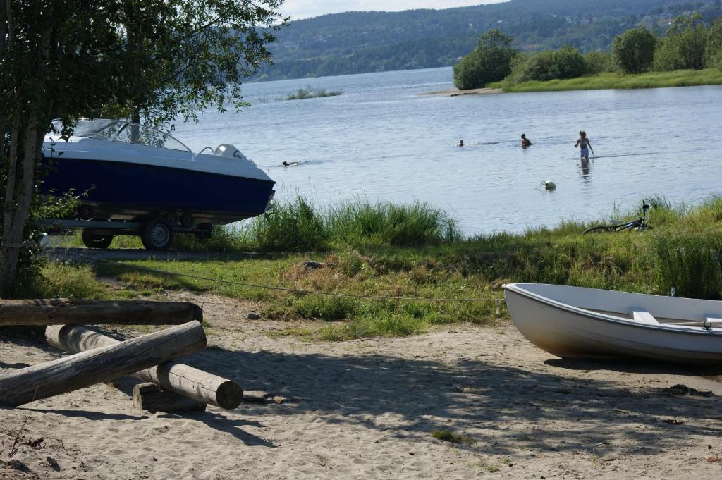 Odin Camping AS في Svensrud: قارب على شاطئ بحيرة مع الناس في الماء
