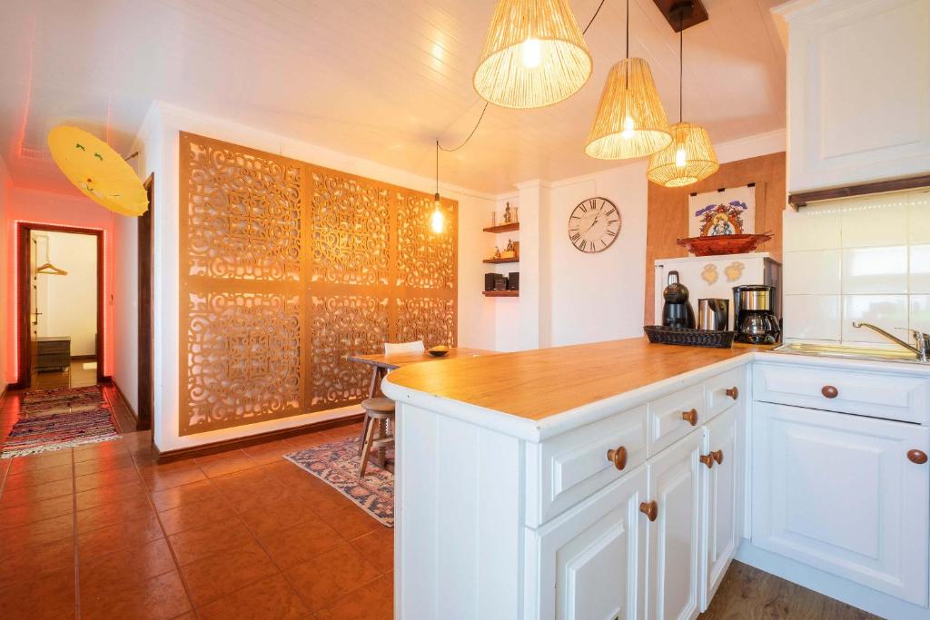 a kitchen with white cabinets and a wooden counter top at epicenter ORIENT in Ponta Delgada