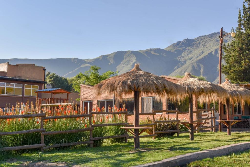 a hut with a grass roof and a fence at Hostería El Remanso in El Mollar