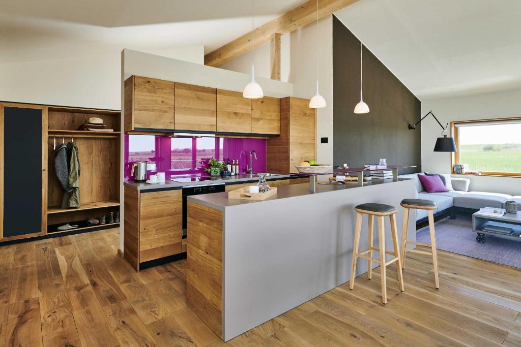 uma cozinha e sala de estar com um balcão e bancos em Gud Jard Lodge Nr 02 - Design-Ferienhaus mit exklusiver Ausstattung em Pellworm