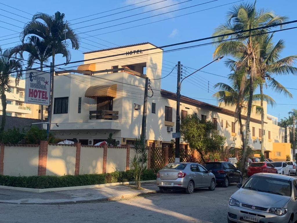 uma rua com carros estacionados em frente a um edifício em Hotel Canto da Enseada no Guarujá