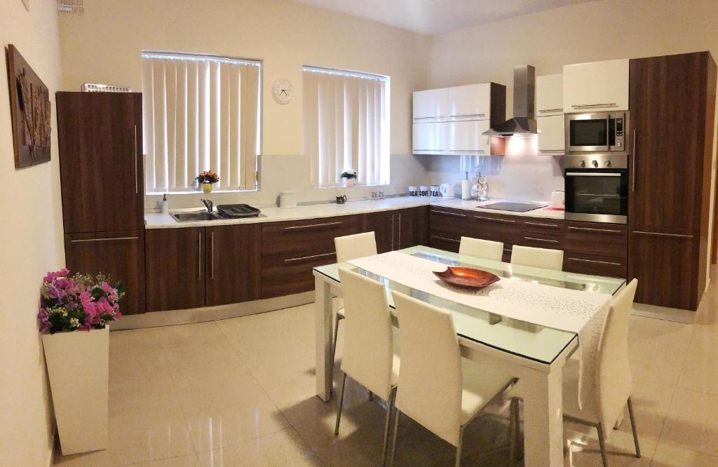 a kitchen with a white table and white chairs at The Village Apartment 2 in Kirkop