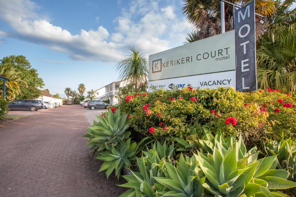 a sign for aza garden court with flowers on a street at Kerikeri Court Motel in Kerikeri