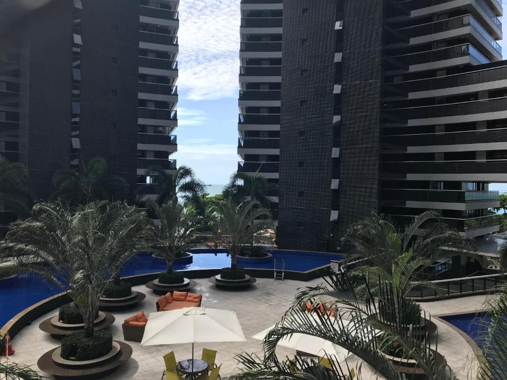uma vista para uma piscina com palmeiras e edifícios em Flat Beira-Mar Landscape em Fortaleza