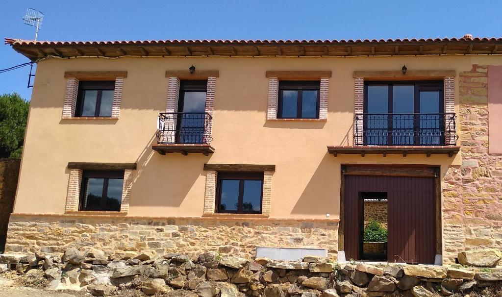 un edificio con varias ventanas y una pared de piedra en Casa Valdequiruelo, en Vanidodes
