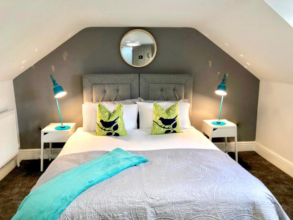 a bedroom with a large bed with two lamps and a mirror at BrickSage Rooms, King's Lynn The Walks in Kings Lynn