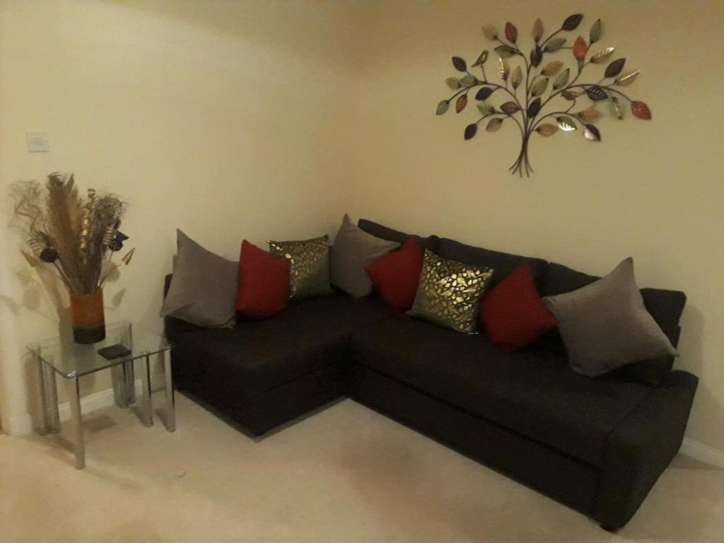 Airdrie Apartments في إيردري: أريكة سوداء مع وسائد ملونة في غرفة المعيشة