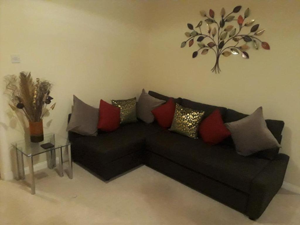 a black couch with colorful pillows in a living room at Airdrie Apartments in Airdrie