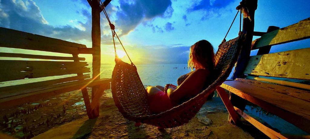 a woman sitting in a hammock watching the sunset at Alegria Dive Resort in Alegria