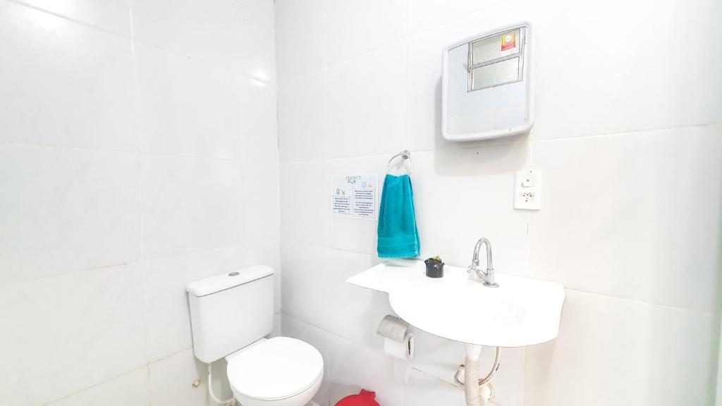 uma casa de banho branca com um WC e um lavatório em Vila da Sereia hostel e pousada em Icaraí