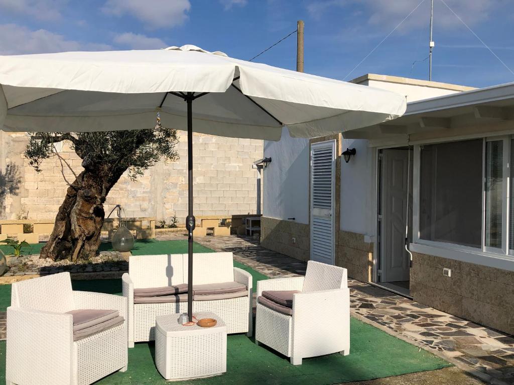 een patio met een witte parasol en stoelen en een huis bij Relais Regina Giulia in Gallipoli