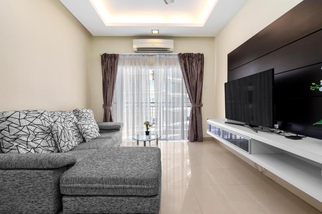 a living room with a couch and a flat screen tv at Windsor Tower by Plush in Kuala Lumpur