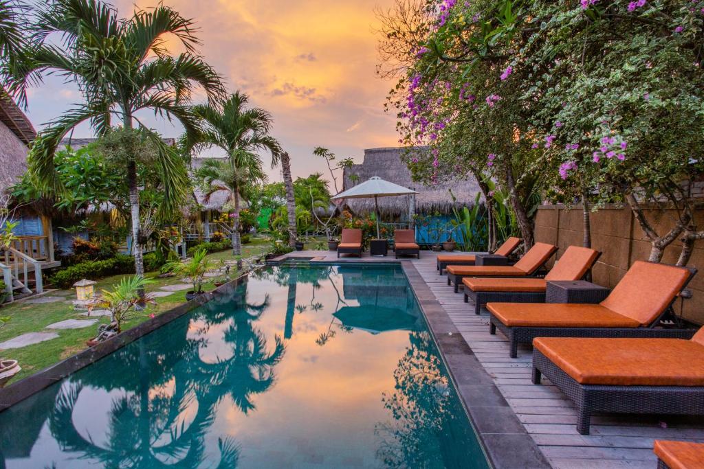 a pool at a resort with lounge chairs and trees at TS Hut Lembongan in Nusa Lembongan