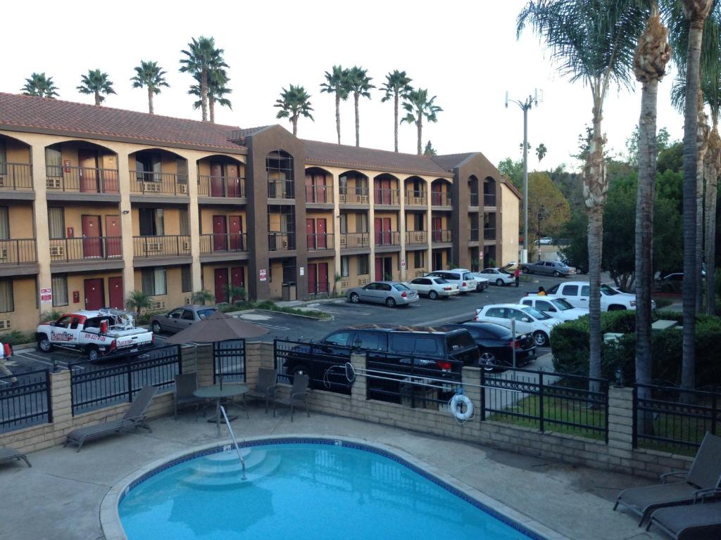 a hotel with a pool in front of a parking lot at Five Star Inn in West Covina