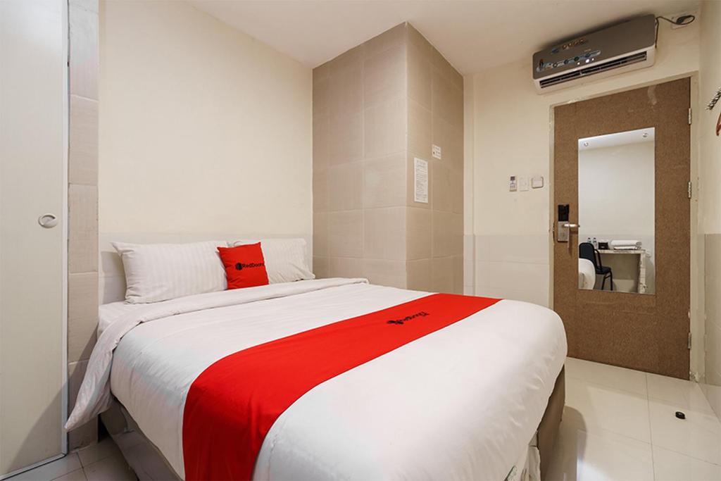 um quarto com uma cama grande e um cobertor vermelho em Permata Inn em Medan