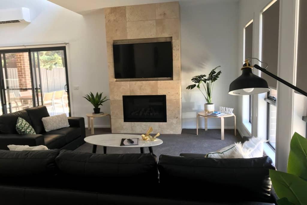 a living room with a black couch and a fireplace at Mountain Mist Apartments in Bright