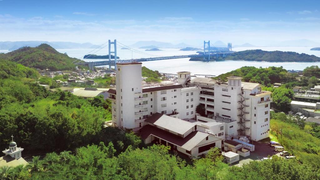 ein Gebäude auf einem Hügel mit einer Brücke im Hintergrund in der Unterkunft Washu Blue Resort風籠 Kasago in Kurashiki