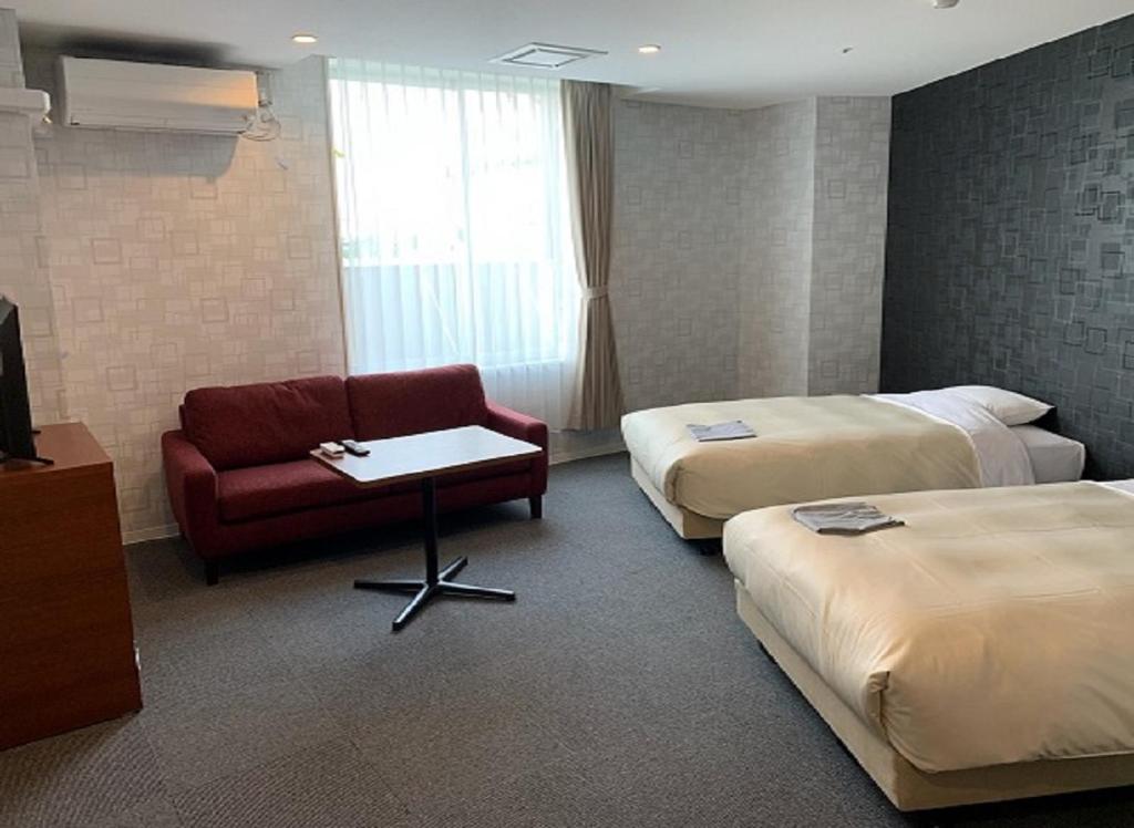Habitación de hotel con 2 camas y sofá rojo en Hotel Crown Hills Kushiro, en Kushiro