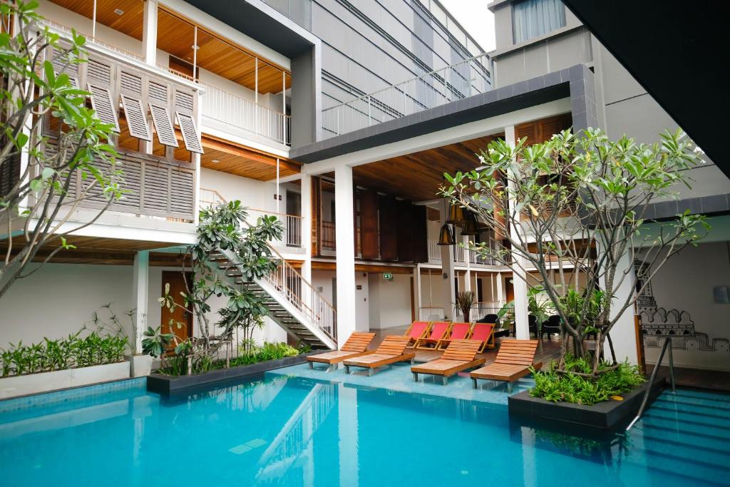 a swimming pool with chairs and a building at Nanda Heritage Hotel in Bangkok