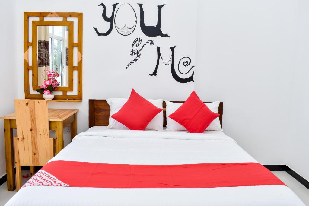 a bedroom with a bed with red and white pillows at Mallika Resort in Trincomalee