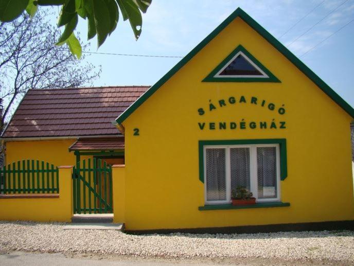 un edificio amarillo con un cartel en el costado en Sárgarigó Vendégház, en Bakonybél