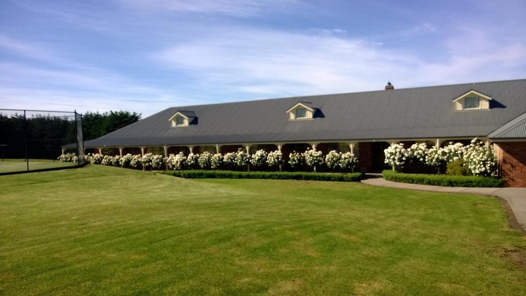 un gran edificio con flores blancas delante de él en Cleggett Estate en Gisborne