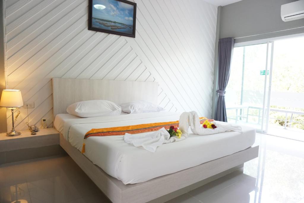 1 dormitorio con 1 cama con sábanas blancas y ventana en แกรนด์ ฟอเรสท์ Grand Forest en Chanthaburi
