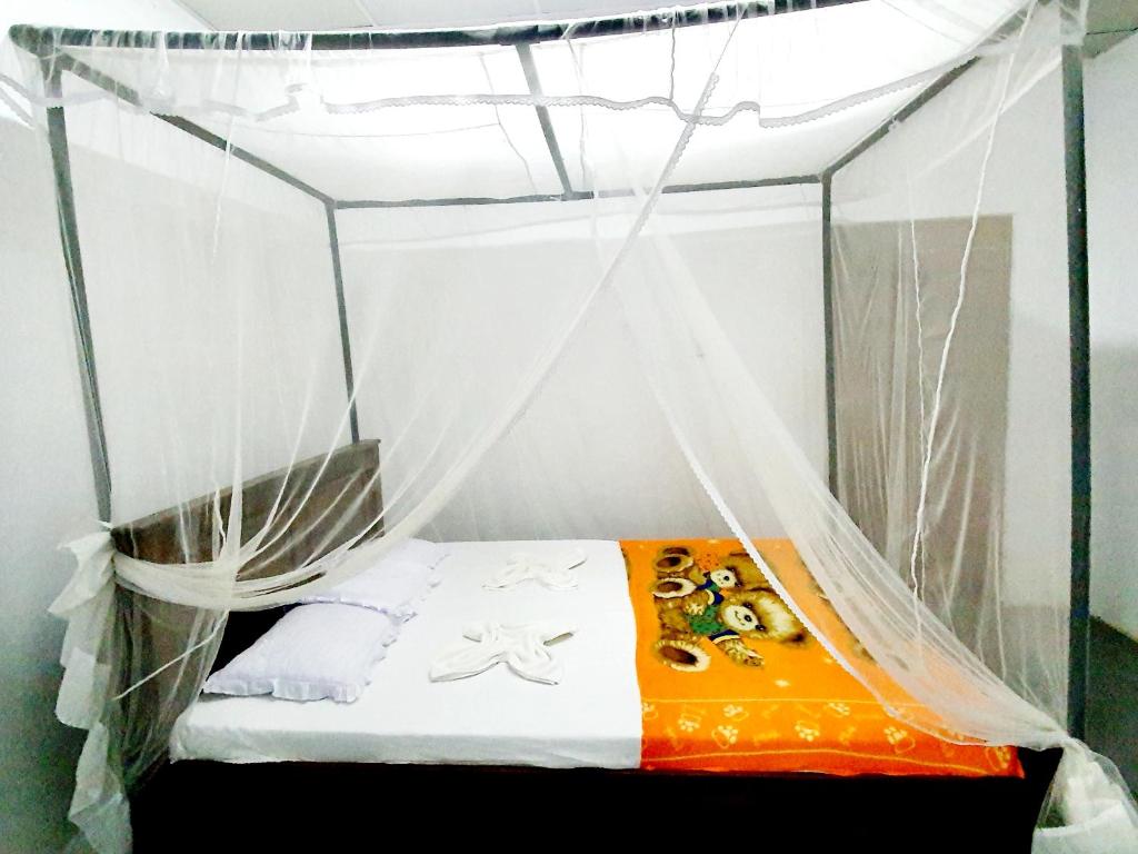 a bed in a canopy in a room at Surfing Waves Madiha in Matara