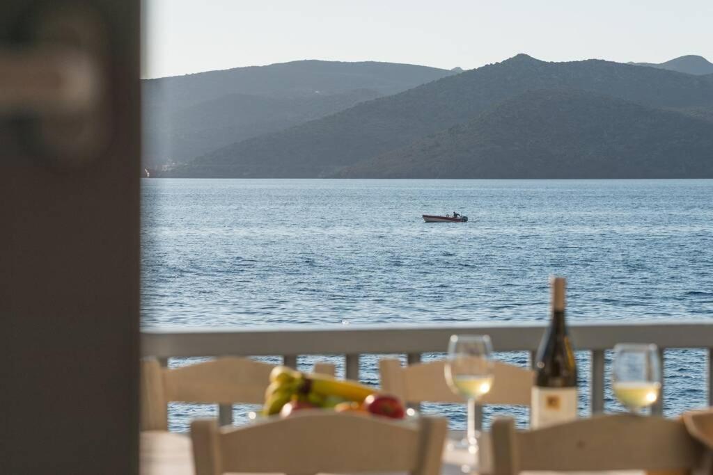 a table with wine glasses and a boat in the water at Capetan Nikolas-boat house in Klima