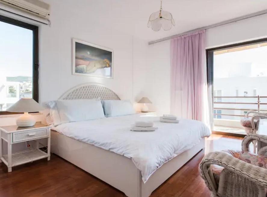 a white bedroom with a bed and a chair at Luxury Athenian Riviera Apartment 135 sqm at Voula in Athens