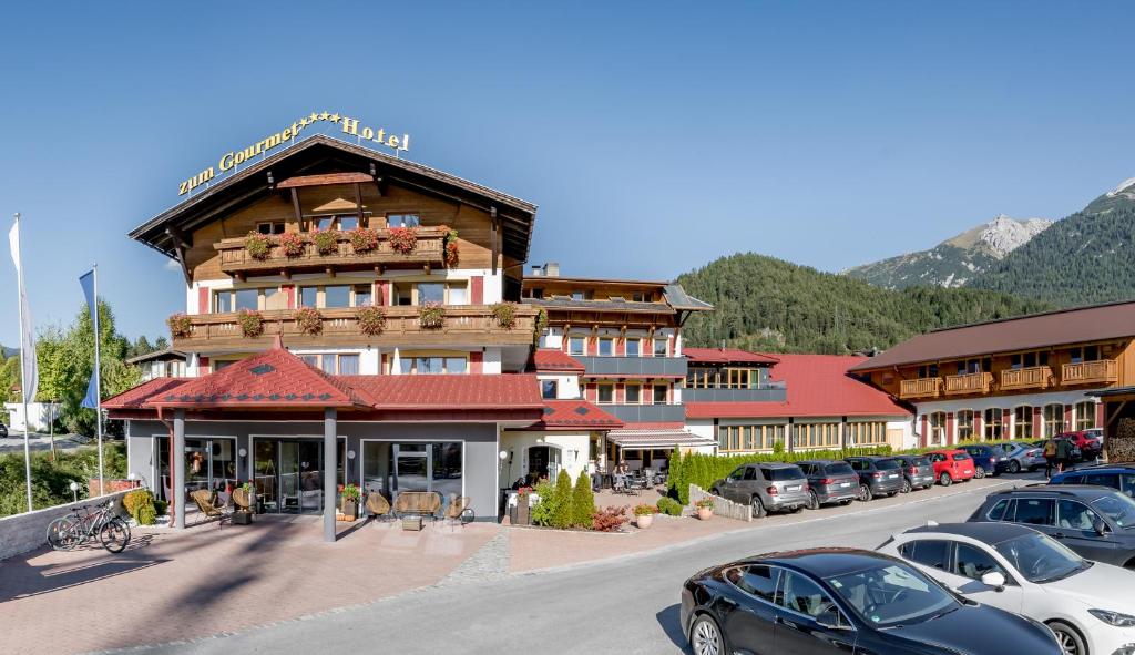 un grand bâtiment avec des voitures garées dans un parking dans l'établissement Hotel Zum Gourmet, à Seefeld in Tirol