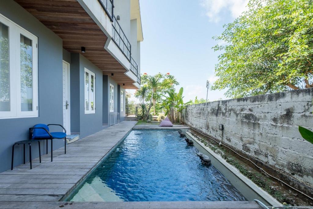 a house with a swimming pool next to a wall at RedDoorz @ Pecatu Ungasan in Uluwatu