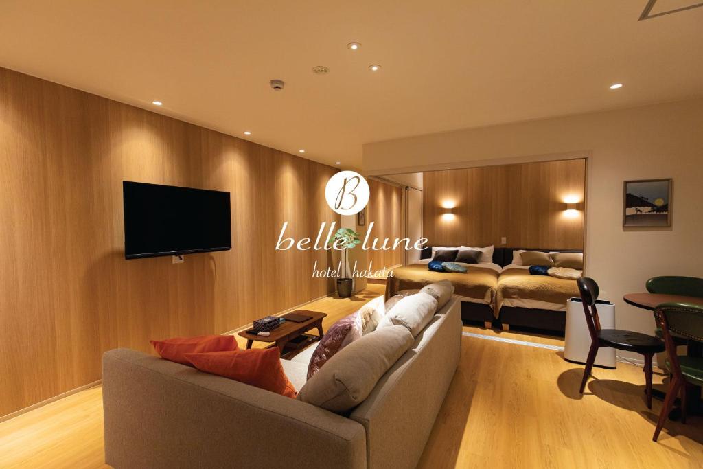 ein Wohnzimmer mit einem Sofa, einem Bett und einem TV in der Unterkunft belle lune hotel hakata Suite Room 1 in Fukuoka