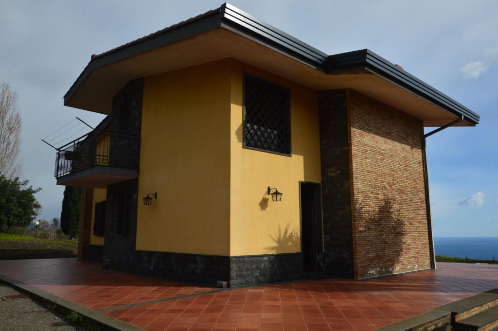 - un petit bâtiment jaune avec un balcon et l'océan dans l'établissement Villa Elena, à Mascali