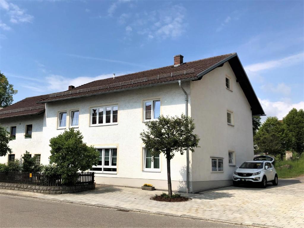 a white house with a car parked in front of it at Ferienwohnung Penzkofer in Zandt