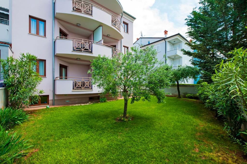 un árbol en un patio frente a un edificio en Apartments and Rooms Camaiore, en Rovinj