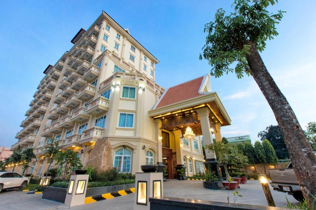 a large building with a palm tree in front of it at Classy Hotel in Battambang