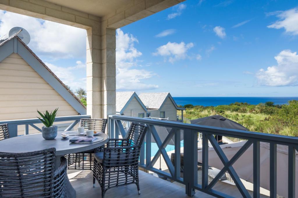 a balcony with a table and chairs and the ocean at West Rock Villas in Saint James