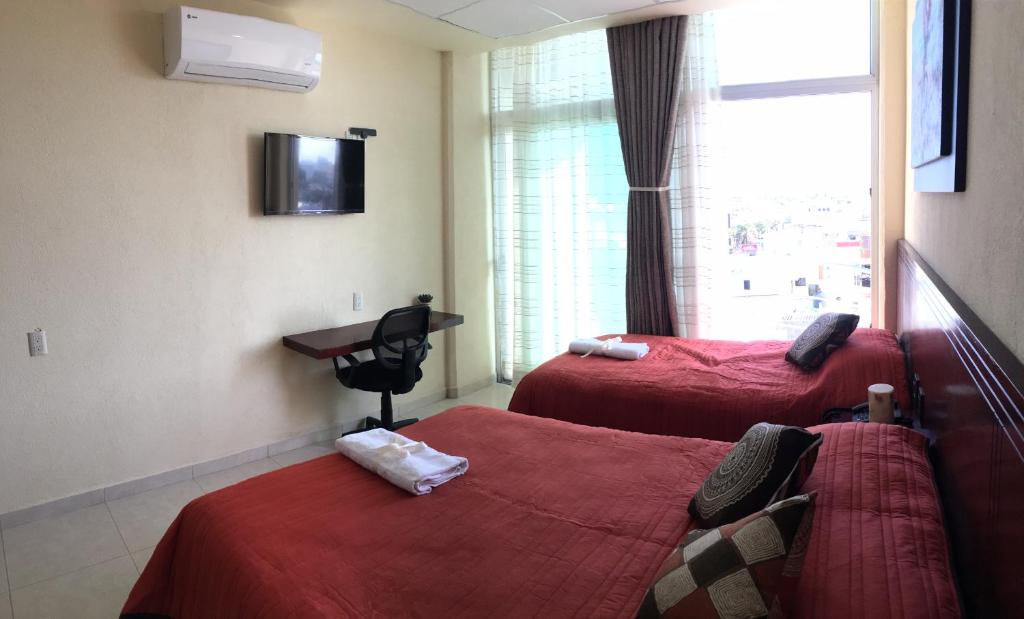 a room with two beds and a desk and a window at Harbour Inn - Veracruz in Veracruz