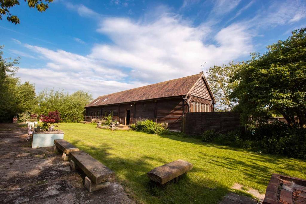 a barn with two benches in front of it at The Timber Barn South Downs West Sussex Sleeps 18 in Hardham