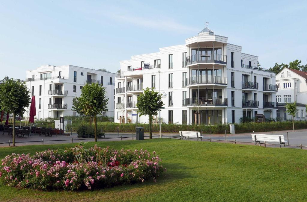 a large white building with a park with benches and flowers at Baabe Villen Ensemble FeWo 02 Kais in Baabe