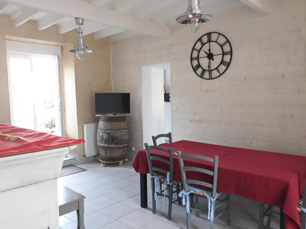 a dining room with a table and a clock on the wall at L'Ancienne Forgerie de Sainte mère Eglise in Sainte-Mère-Église