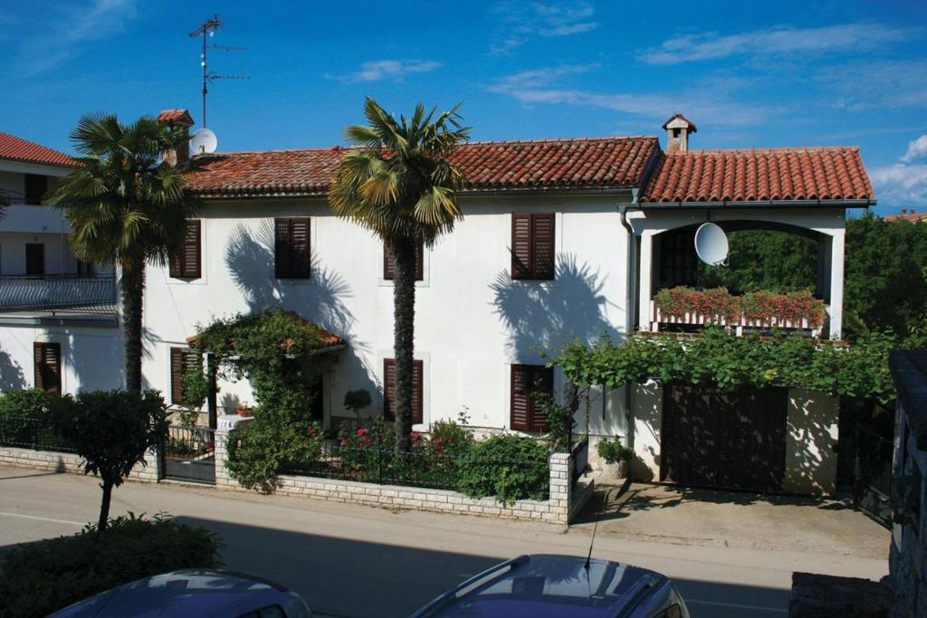 a white house with a palm tree in front of it at Anamarija Apartments near the beach and the fantastic Adria Sea with over 10 small islands close by in Funtana