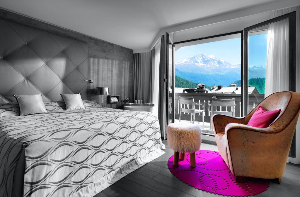 1 dormitorio con 1 cama, 1 silla y balcón en Giardino Bed & Breakfast, en Silvaplana
