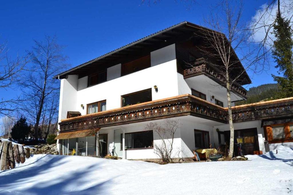 una casa bianca con un tetto nero nella neve di Haus Pfauth a Tannheim