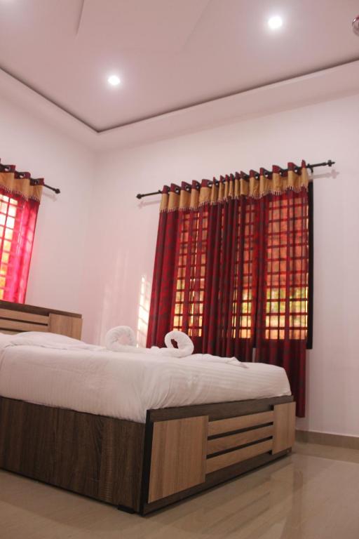 a bedroom with a large bed with red curtains at Wayanad Days in Mananthavady